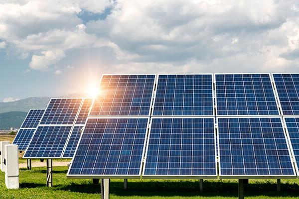 能量转换——太阳能电池板安装在蓝天的草地上. 阳光从太阳能板的边缘反射出来.