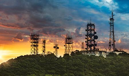 日落时山上的天线塔和通信中继器的剪影.
